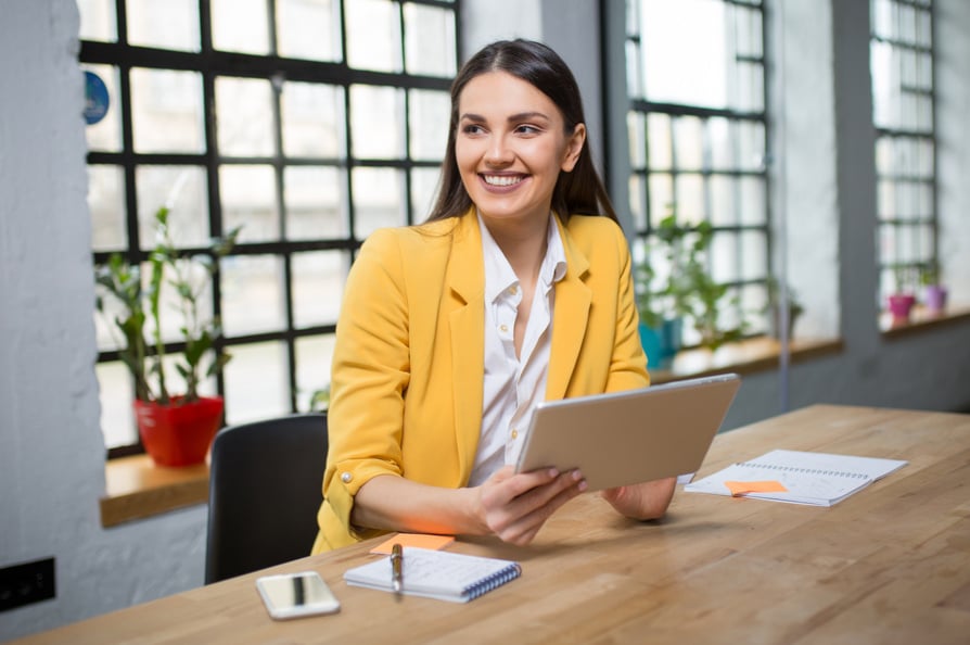 Young happy entrepreneur woman using digital tablet at office